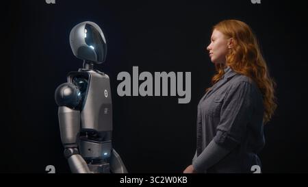 Futuristic Human-Machine Concept: Visualization of Young Woman Speaking with High-Tech Humanoid Robot. Symbol of Connection, Collaboration and Harmony Between Humanity and Artificial Intelligence. Stock Photo