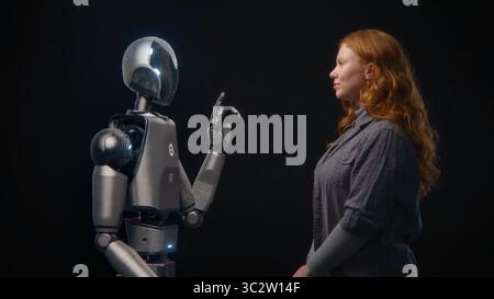Futuristic Human-Machine Concept: Visualization of Young Woman Speaking with High-Tech Humanoid Robot. Symbol of Connection, Collaboration and Harmony Between Humanity and Artificial Intelligence. Stock Photo
