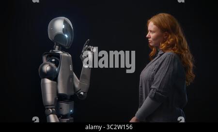 Futuristic Human-Machine Concept: Visualization of Young Woman Speaking with High-Tech Humanoid Robot. Symbol of Connection, Collaboration and Harmony Between Humanity and Artificial Intelligence. Stock Photo