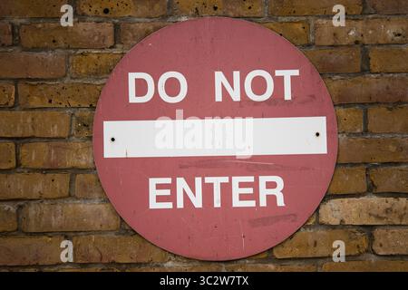 Red "DO NOT ENTER" sign mounted on a wall, serving as a clear warning or restricted access notice in a public or private area. Stock Photo