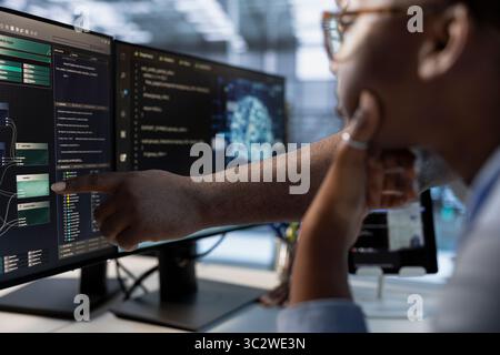 Technician teaches colleague to do data center automation using AI and machine learning tools. African american employees integrating artificial intelligence driven automation in server hub operations Stock Photo