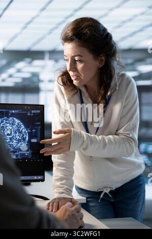 Teamworking engineers using artificial intelligence technology to optimize data center workplace. Colleagues talking in server hub, using AI tech to streamline operations and forecast issues Stock Photo