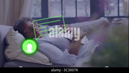 Resting woman wearing long-sleeve shirt holding book on sofa at home, with chat and avatar overlays Stock Photo