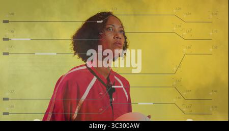 Showcasing woman in red jersey holding soccer ball at hip in yellow fog studio, analytics overlay Stock Photo