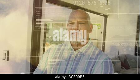 Standing man wearing striped shirt scanning data panels near sliding glass door at living room Stock Photo