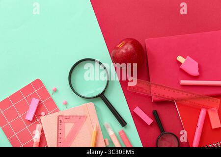 Fresh apple with magnifiers and different stationery on color background Stock Photo