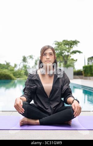 Transgender woman performing yoga poses outdoors by pool, showcasing ...