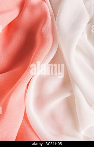 Elegant background of silk fabric in peach and white. Delicate soft waves of fabric intertwine with each other. Chic vertical background. Stock Photo