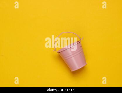 Pink empty mini bucket on yellow background. Minimalism. Trend color concept. Top view Stock Photo