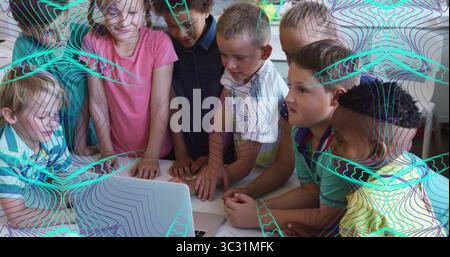 Huddling eight classmates leaning over laptop at classroom table, with scattered papers and pen Stock Photo