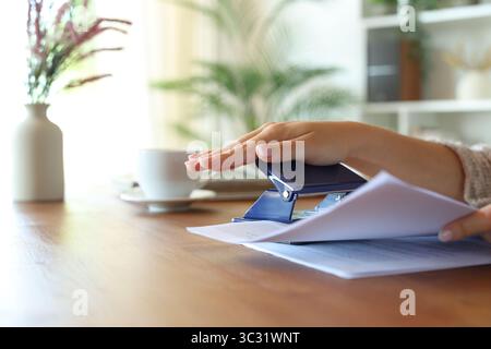 Close up of a woman hands doing holes with paper punch on sheets at home Stock Photo