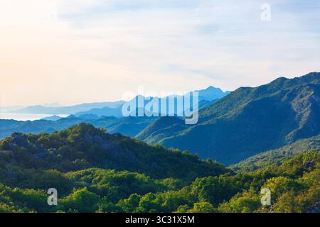 Vast panorama of layered mountains, fading into a soft blue haze. Rugged beauty of the mountain range, stretching into the soft light of the morning. Stock Photo