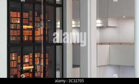 Aged books lined up on rustic wooden bookshelves in an old library interior. Stock Photo