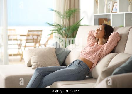 Woman relaxing and resting sitting on a couch in the living room at home Stock Photo