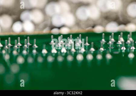 old circuit board with a large number of contacts, a simple green printed circuit board with an electronic circuit with soldered elements Stock Photo