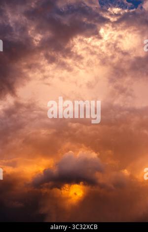 Stormy clouds illuminated by sunset golden light. Dramatic sky in extreme weather. Cloudscape thunderstorm background Stock Photo
