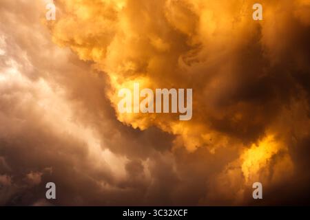 Dark golden storm cloud with towering cumulonimbus. Cloudscape in dramatic sky. Extreme weather Stock Photo