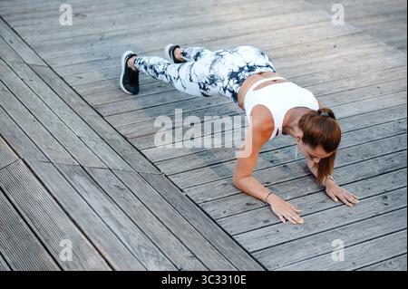 Woman Doing Push-Ups on Wooden Deck Stock Photo