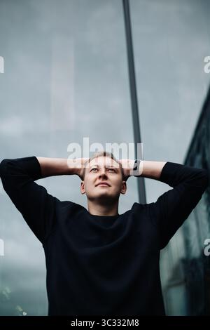 Confident man looking up with hands behind head Stock Photo