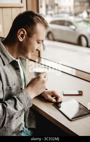 Man drinking coffee and using tablet in cafe Stock Photo