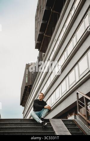 Man sitting on stairs near modern architecture Stock Photo