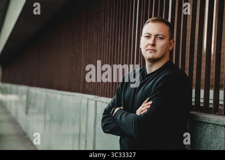 Man standing with arms crossed near modern wall Stock Photo