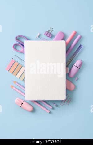 Composition of various school and office stationery in pastel pink and purple colors on a blue background. Place for your text. Stock Photo