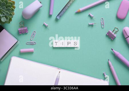 Word Tips in English made of wooden blocks on a background of purple stationery. Mint green backdrop. Stock Photo