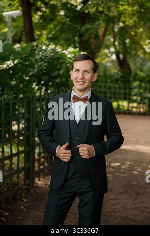 Man in formal attire smiling in a park setting Stock Photo