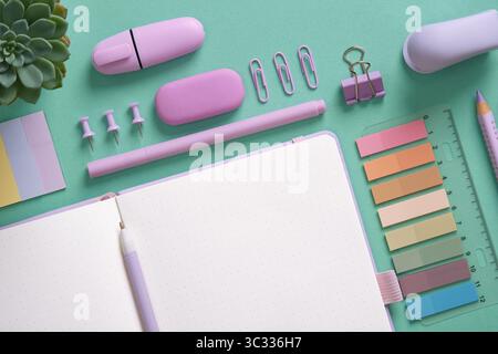 Empty notebook page for your text with violet school and office stationery on mint green background. Space for your text. Stock Photo