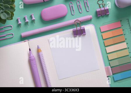Empty notebook page for your text with violet school and office stationery on mint green background. Space for your text. Stock Photo