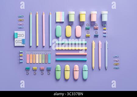 Pastel-colored stationery neatly arranged on a light purple background. Workplace organization. Back to school concept. Stock Photo