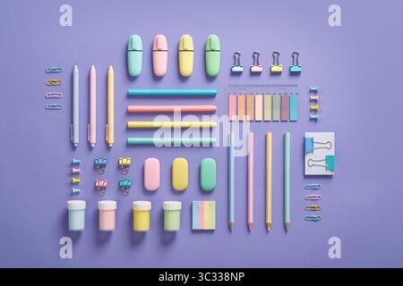Pastel-colored stationery neatly arranged on a light purple background. Workplace organization. Back to school concept. Stock Photo
