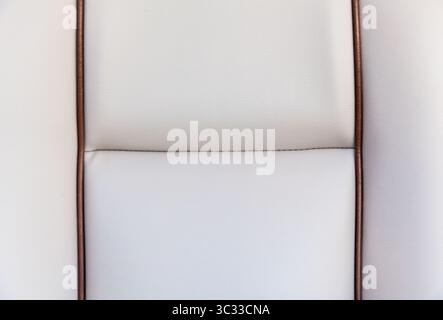 Texture of a white leather chair upholstery with brown accents close-up. White leather background. Stock Photo