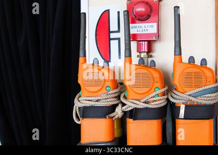 Three orange emergency radios on a ship near an alarm. Apply in case of general or fire alarm. Stock Photo