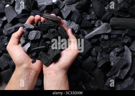 Man with black coals over pile, top view Stock Photo