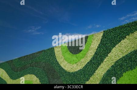The green wall is made of various types of artificial plastic plants and different shades of green and blue sky Stock Photo