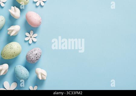 Composition with Easter eggs, bunnies and wooden flowers on blue background. Place for your text. Stock Photo