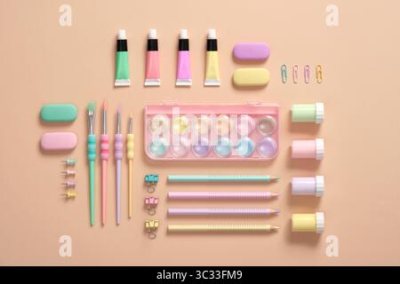 Various pastel-colored materials for creativity and art activities are neatly arranged on a beige background. Organization of the workplace. Back to s Stock Photo