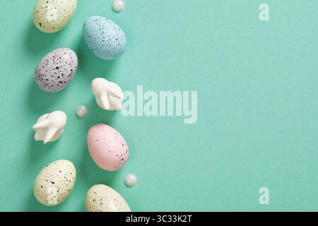 Easter background with eggs, bunnies and wooden flowers on mint green background. Place for your text. Stock Photo
