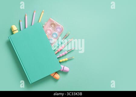 Composition of various school and office stationery in pastel mint green and purple colors on a blue background. A Place for your text. Stock Photo