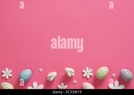 Easter background with eggs, bunnies and wooden flowers on pink background. Place for your text. Stock Photo