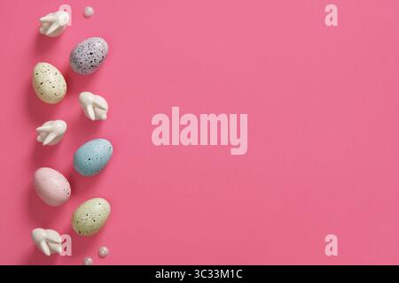 Easter background with eggs, bunnies and wooden flowers on pink background. Place for your text. Stock Photo