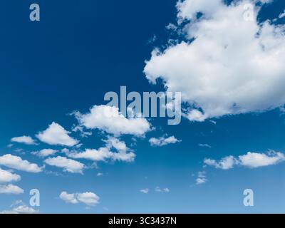 Beautiful display of white puffy clouds against a clear blue sky on a sunny day. Stock Photo