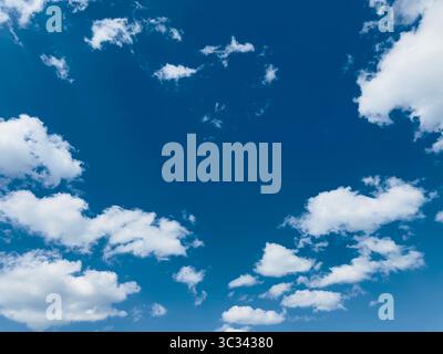 Beautiful display of white puffy clouds against a clear blue sky on a sunny day. Stock Photo
