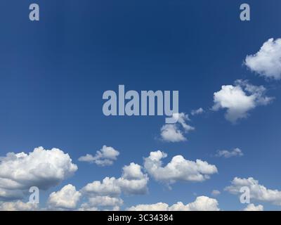 Beautiful display of white puffy clouds against a clear blue sky on a sunny day. Stock Photo