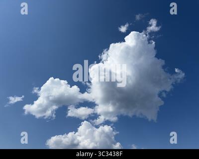 The bright blue sky is filled with beautiful fluffy white clouds on a sunny day. Stock Photo
