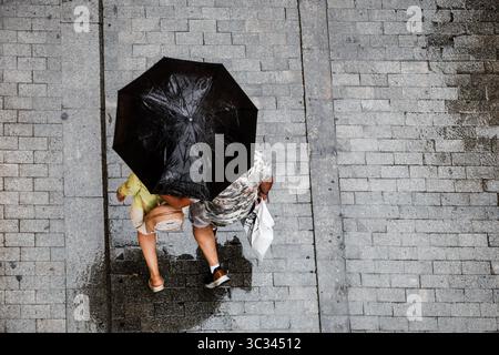 Two people walking with an umbrella on a rainy day. Stock Photo