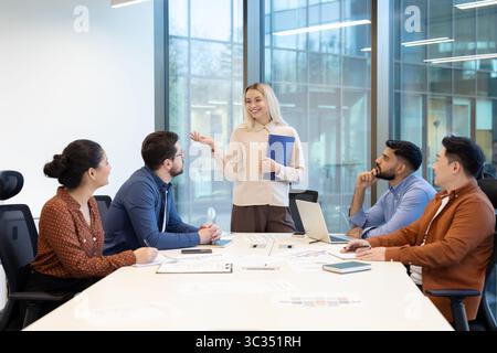 A diverse group of business professionals are collaborating in a modern office setting during a meeting. Stock Photo