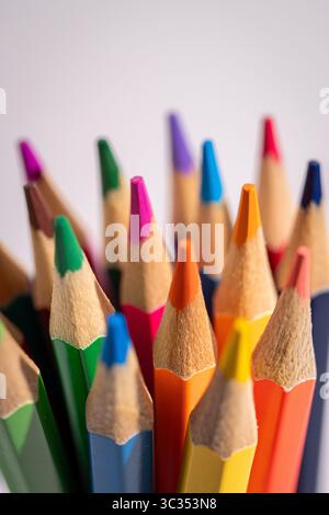 A bunch of colored pencils are lined up in a row. The pencils are of different colors and sizes, and they are all sharpened. Concept of creativity and Stock Photo